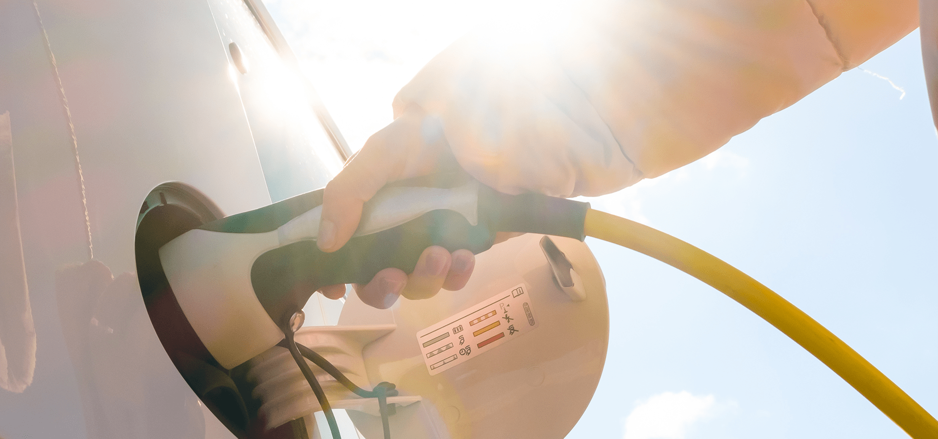 Hand steckt Ladekabel in Elektroauto – E-Auto laden mit Wallbox, PV-Strom und staatlicher Förderung 2026